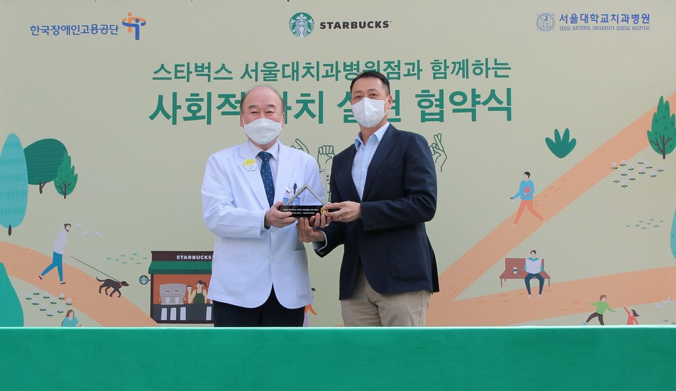 구영 서울대치과병원장(사진 왼쪽)이 송호섭 스타벅스 코리아 대표(오른쪽)에게 감사패를 전달하고 있다.